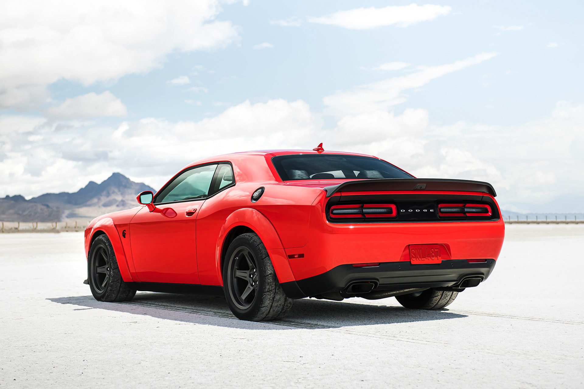 The rear view of a red 2022 Dodge Challenger, parked outdoors with mountains in the background.