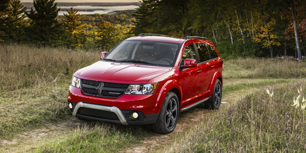 Red 2020 Dodge Journey driving through a grassy field in the forest