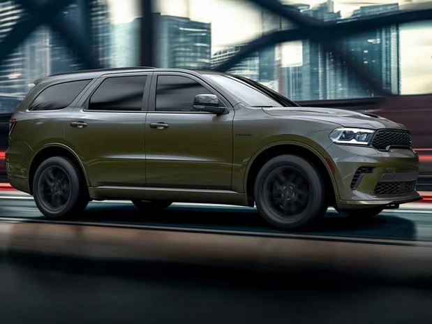 Dodge Durango 2026 roulant en ville avec un arrière-plan urbain flou et des lumières soulignant son profil élégant.