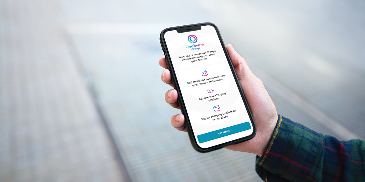 Une personne tenant son téléphone et l'application de charge free2move est ouverte. Explorez «&nbsp;Charge&nbsp;Home&nbsp;»
