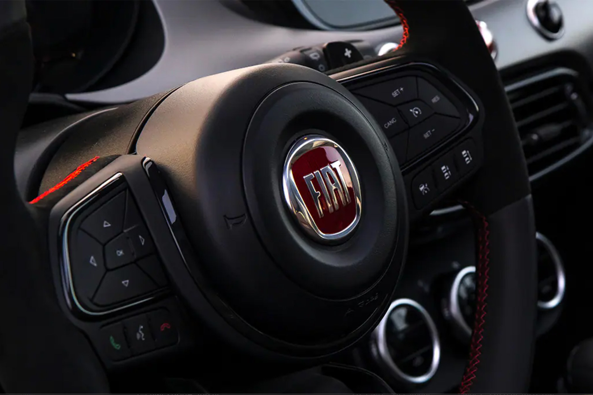 Driver side view of the steering wheel with black trim inside the 2023 Fiat 500X.