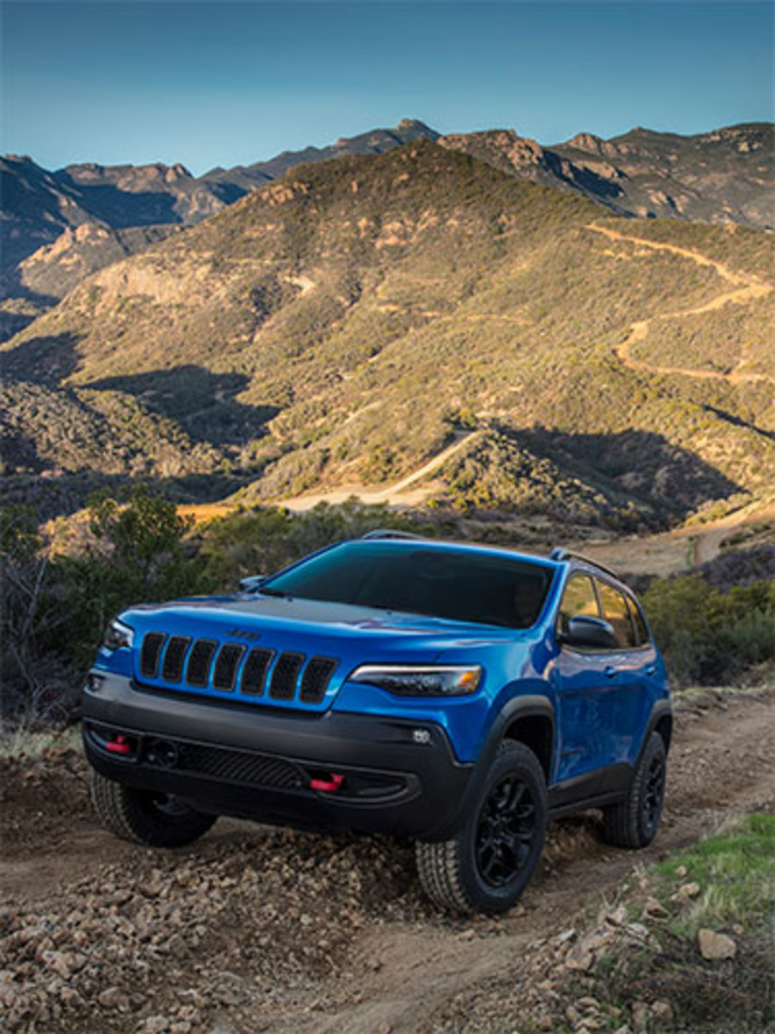 An angled view of a blue Cherokee being driven up a mountain.