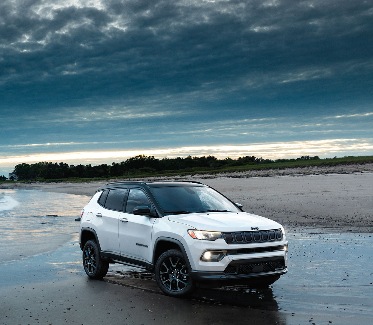 A white 2024 Jeep Compass parked on the beach.