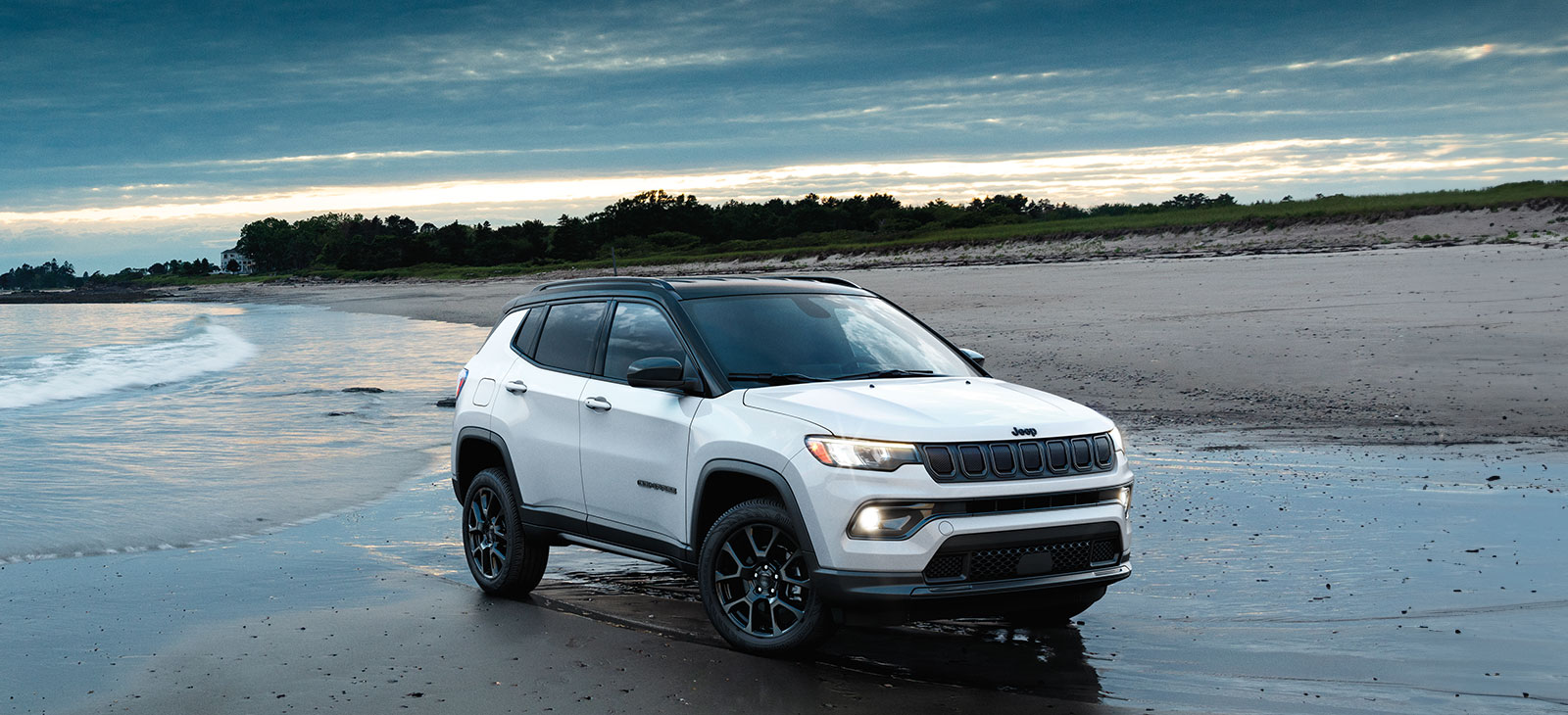 A white 2024 Jeep Compass parked on the beach.
