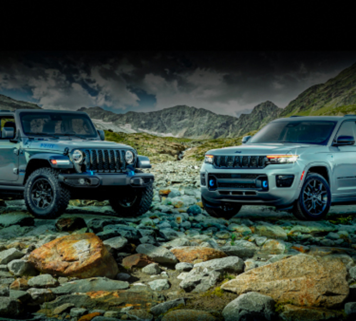 View of two 2023 Jeep Electric vehicle models parked on a rocky terrain.