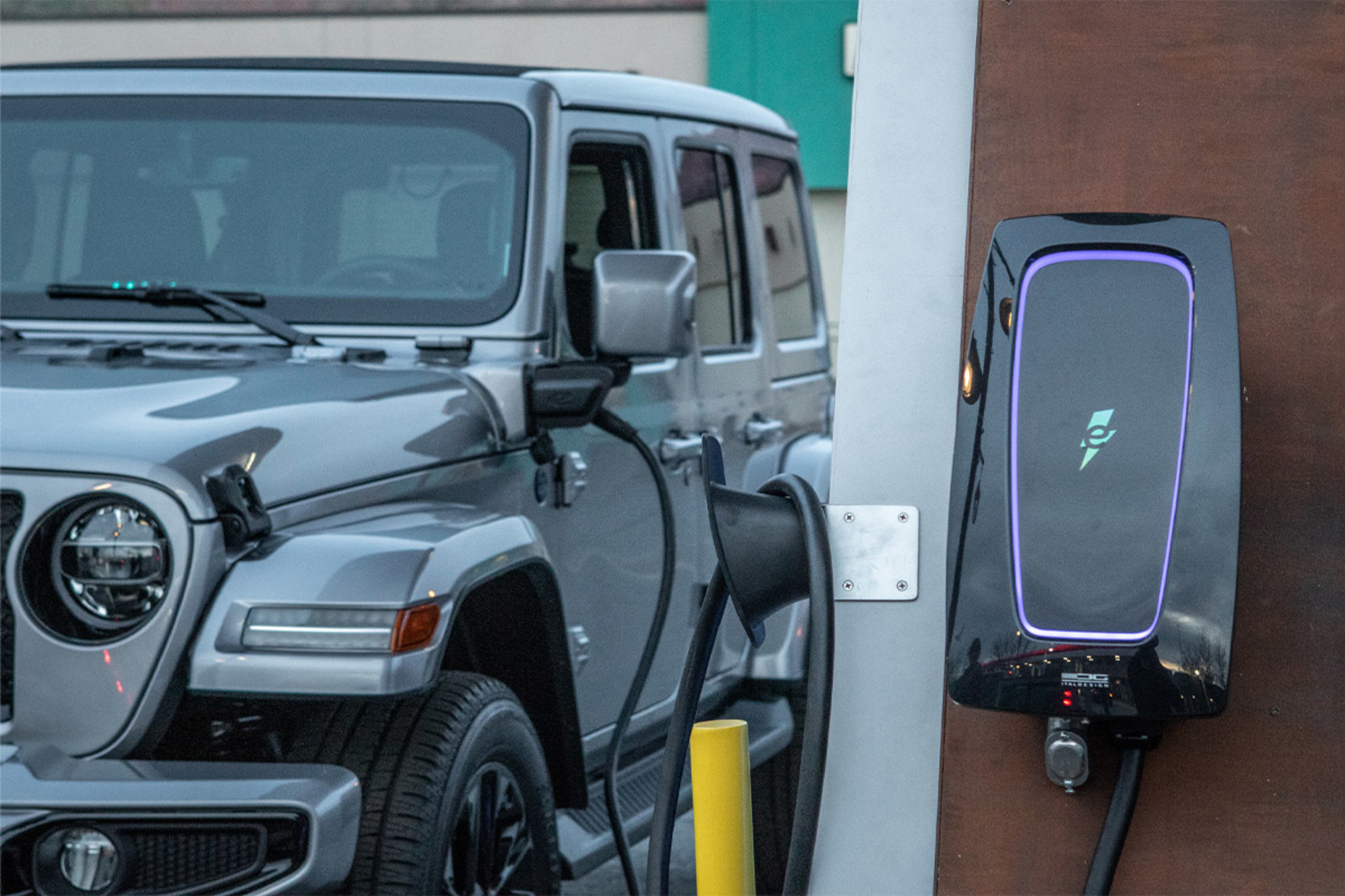 Vue rapprochée d’un Jeep Grand Cherokee 4xe VHR 2023 gris en cours de recharge avec la borne de recharge visible.