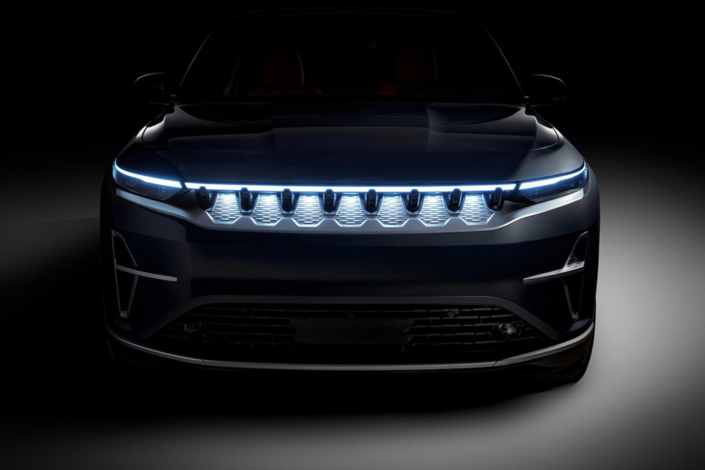 A close-up view of the grille and illuminated headlights on a Jeep Wagoneer S BEV.