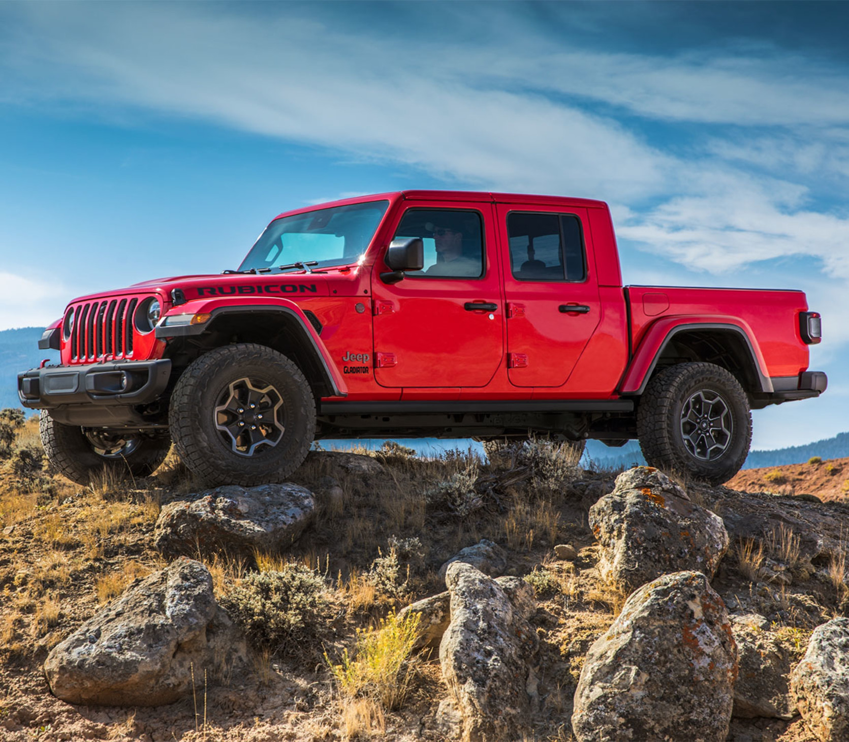 A red 2023 Jeep Gladiator parked on top of rocky terrain.