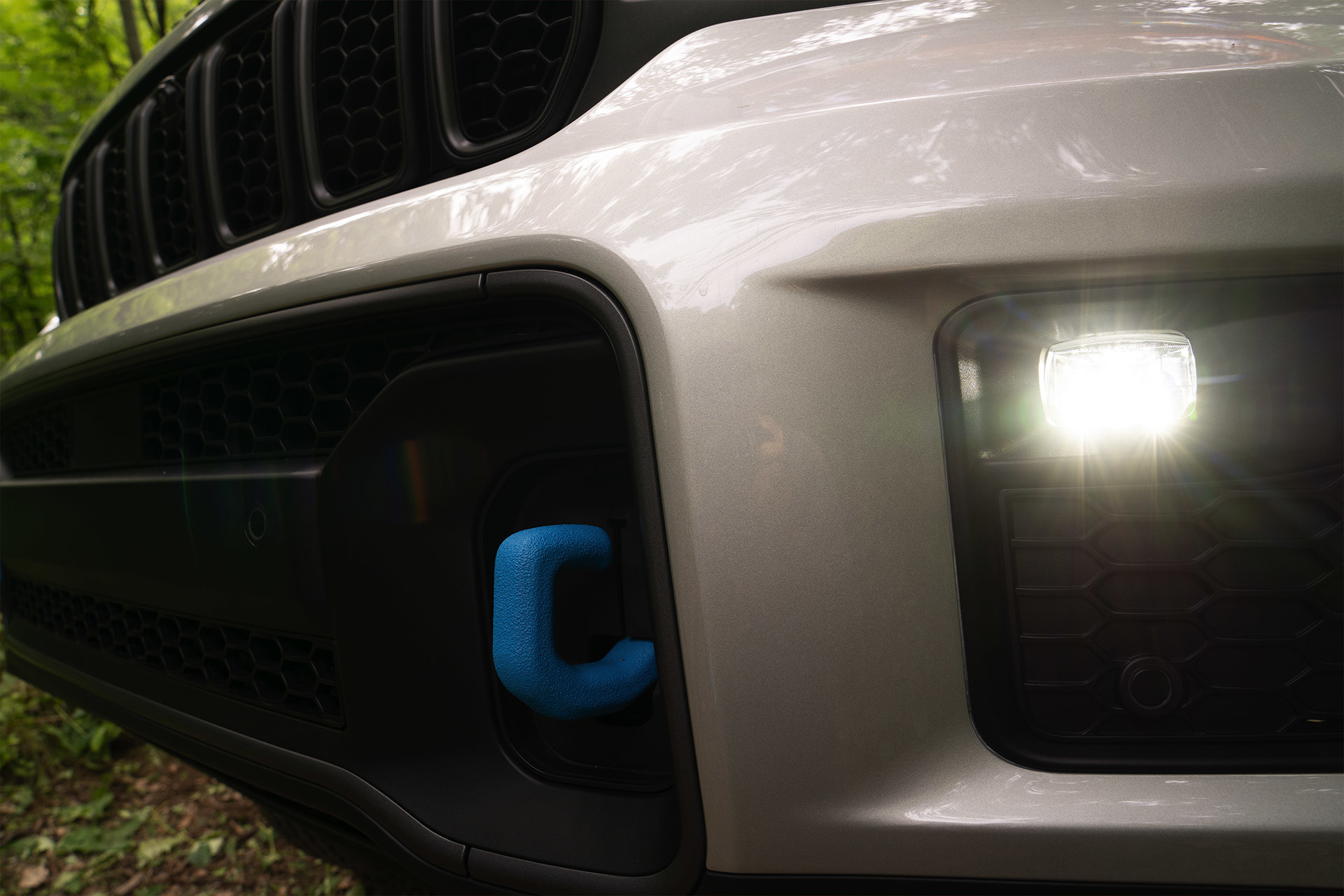 Close-up of the blue tow hooks on the front of a white All-New 2022 Jeep Grand Cherokee 4xe.