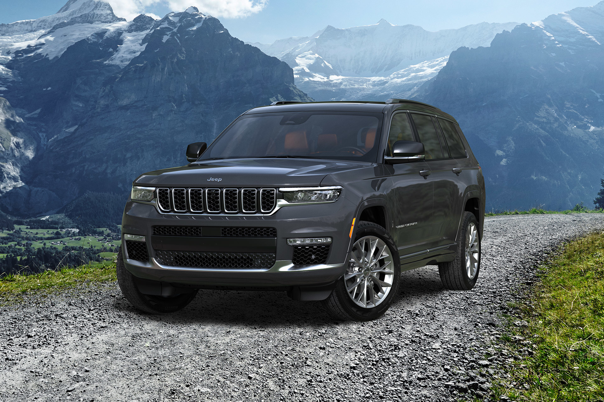 A grey 2022 Jeep Grand Cherokee parked on a gravel road with mountains in the background