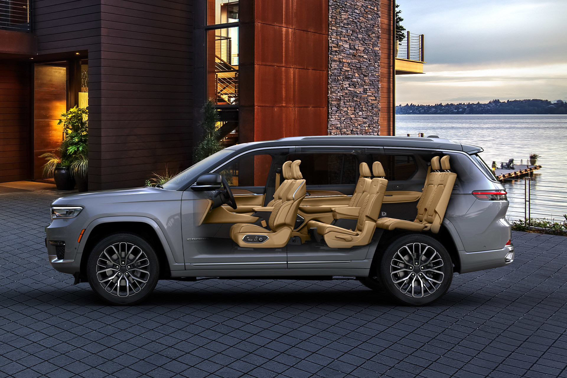 A parked silver 2022 Jeep grand Cherokee L parked in front of a modern house, with a view of the interior of the vehicle.