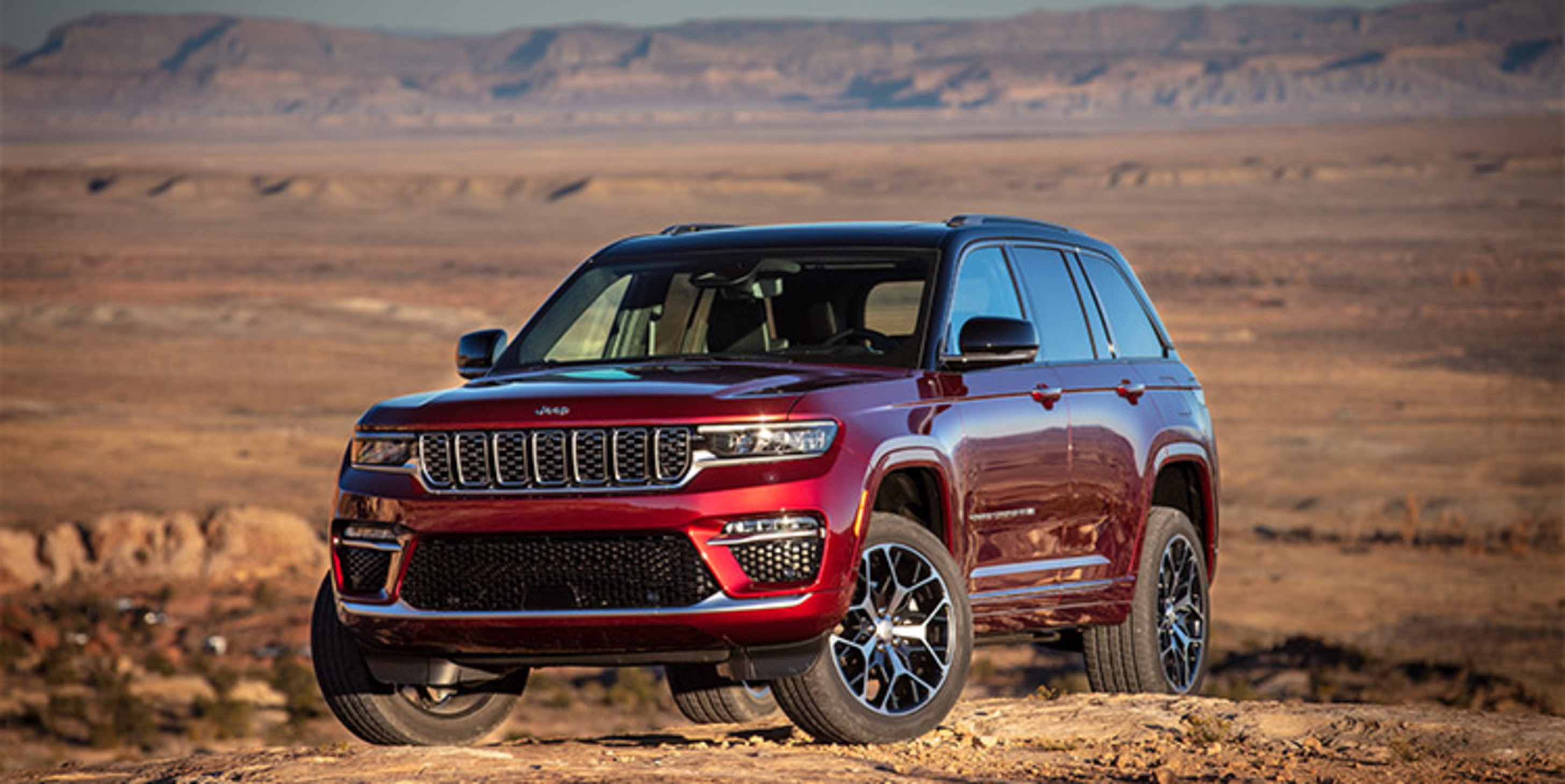Jeep Grand Cherokee rouge 2023 garé au sommet d’une colline sur fond de désert.