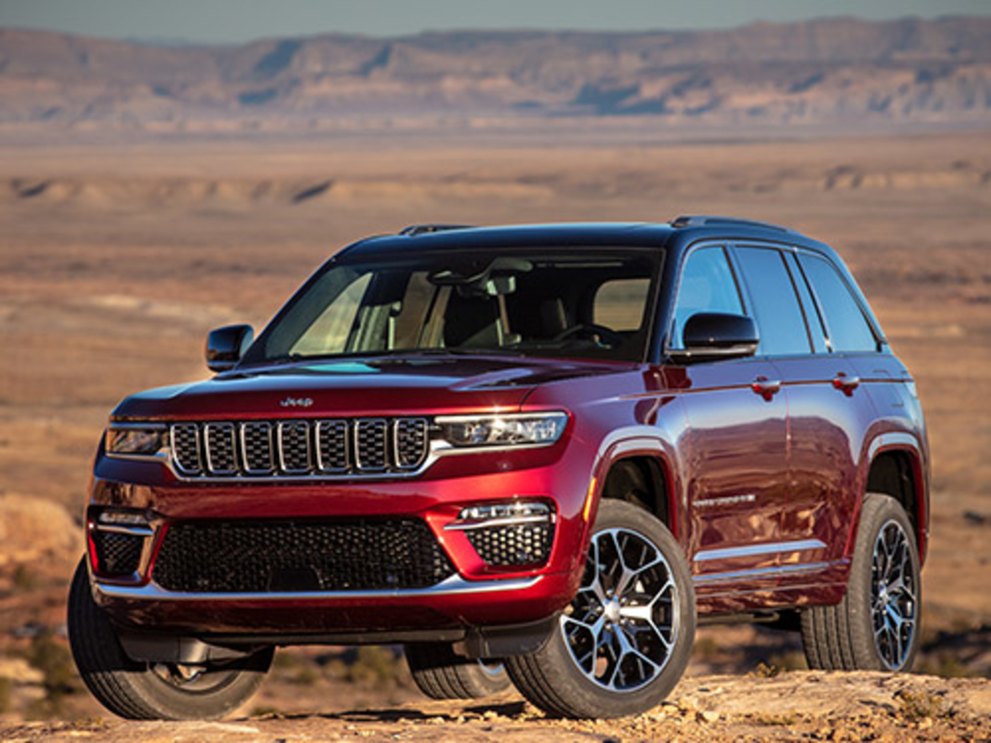 Red 2023 Jeep Grand Cherokee parked on top of hill with desert background.