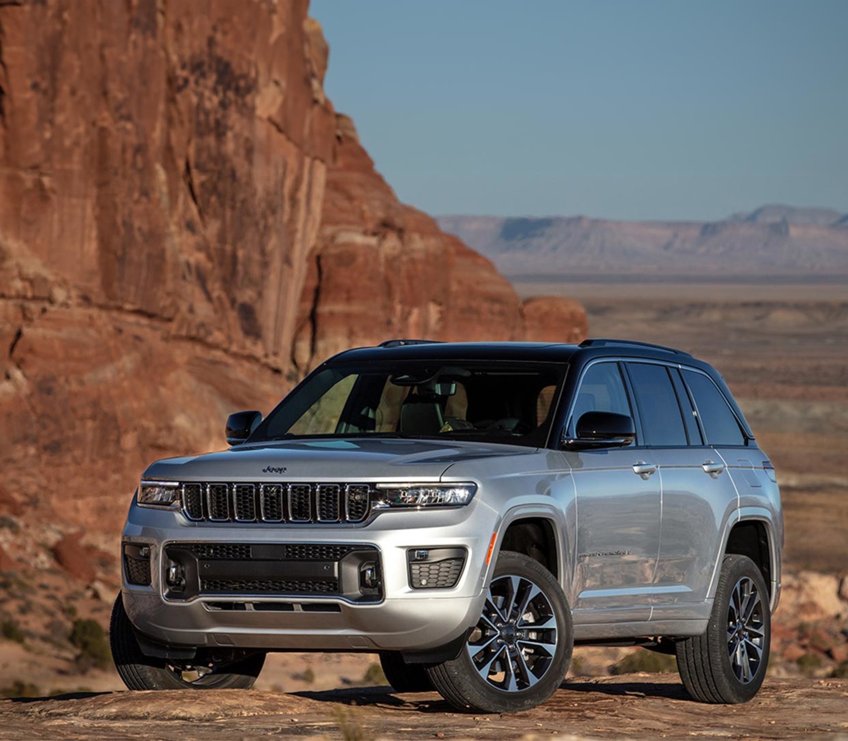 View of a silver 2024 Jeep Grand Cherokee shown parked on desert terrain.