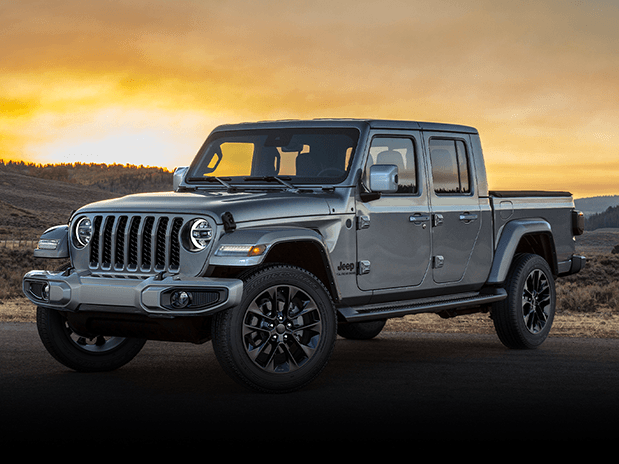 The front driver side of a grey Jeep Gladiator parked in front of a sunset