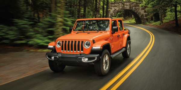Orange 2021 Jeep Wrangler being driven through a forest
