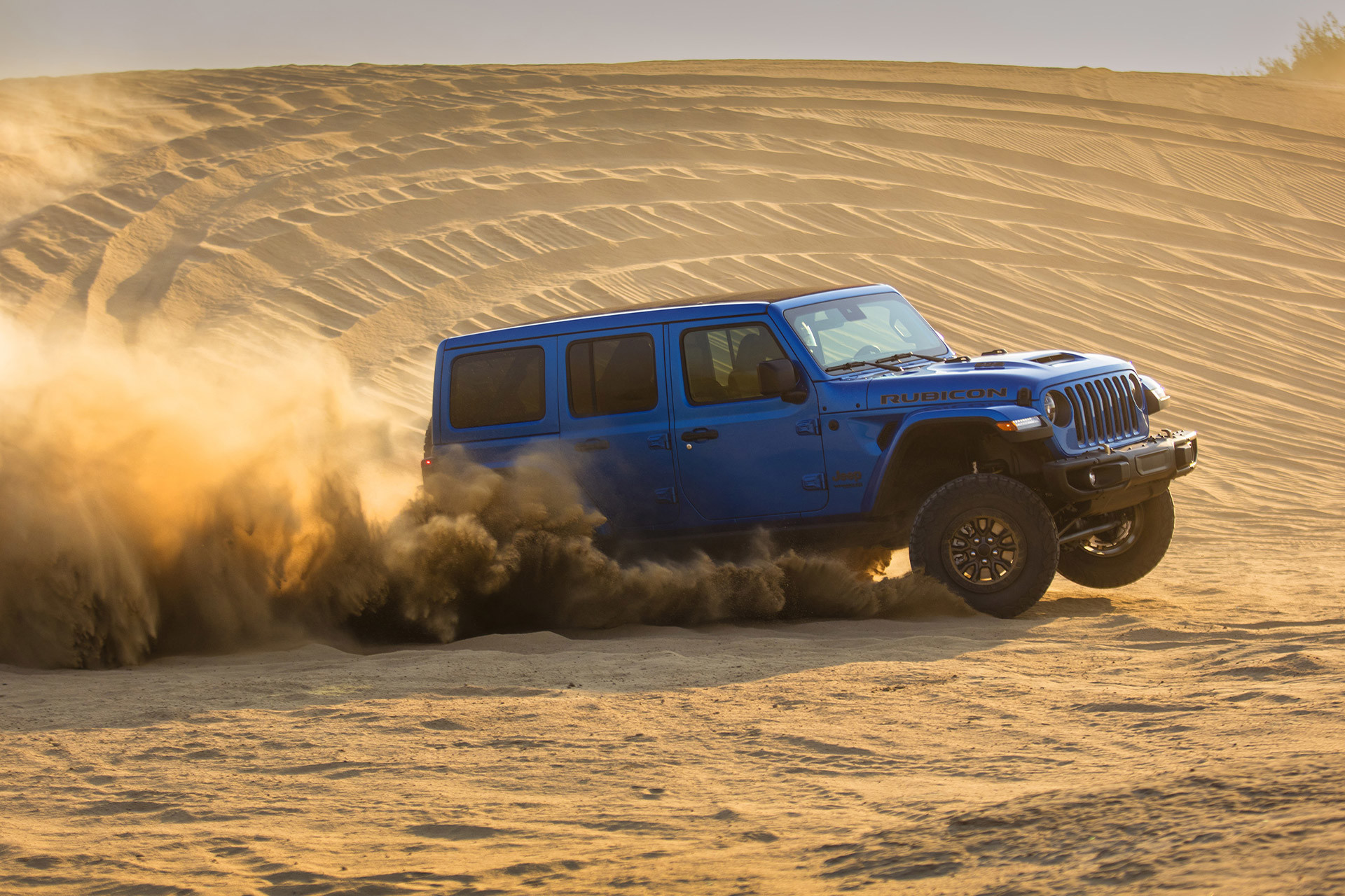 Blue Jeep Wrangler Rubicon 392 drifting through the sand