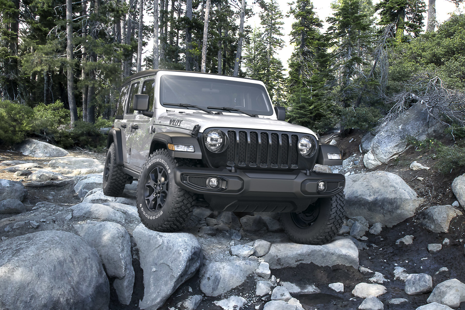 White 2022 Jeep Wrangler parked on rocky terrain in a forest area