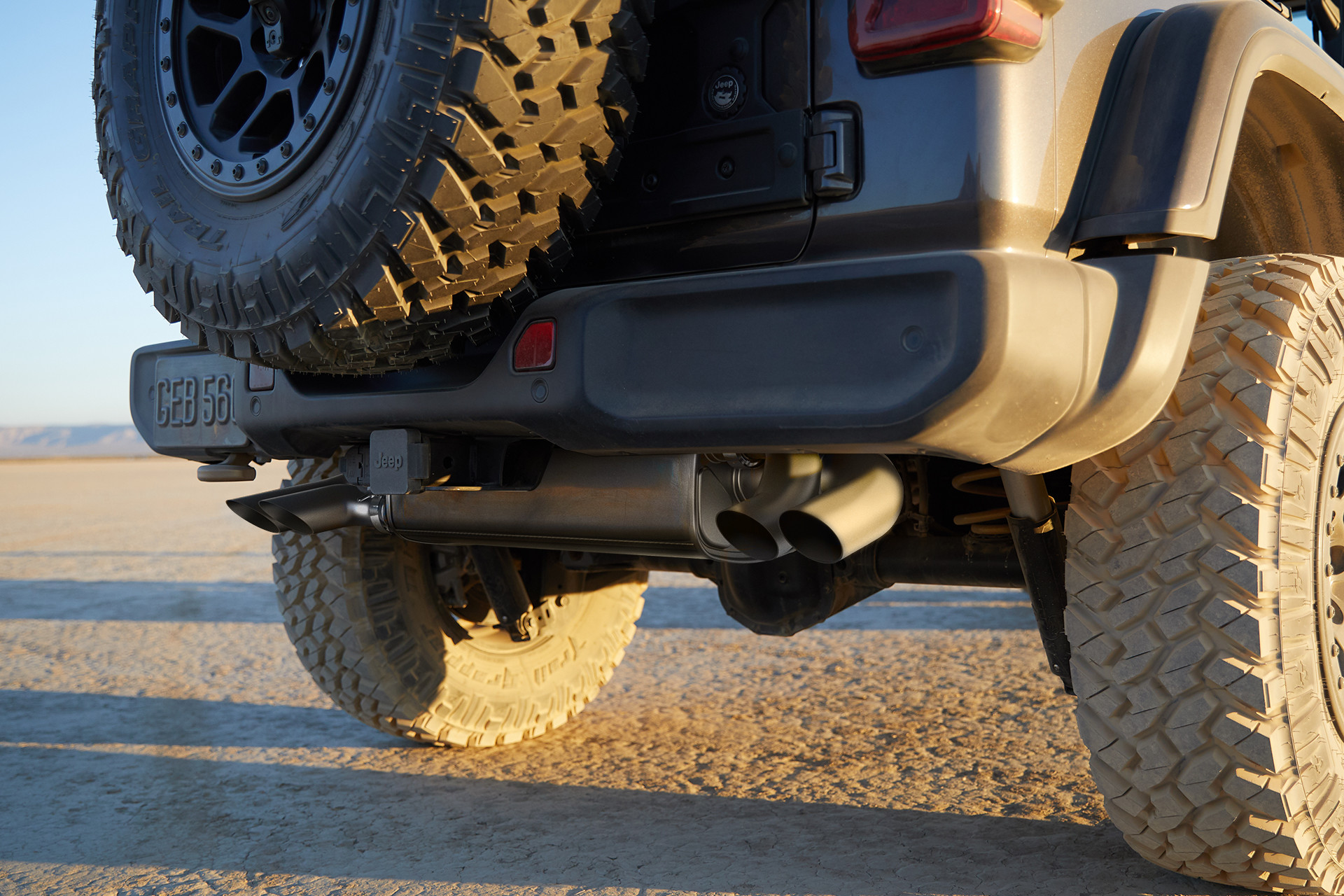 2022 Wrangler Rubicon 392 in Granite parked on sand, close up of exhaust and dusty rear wheels.