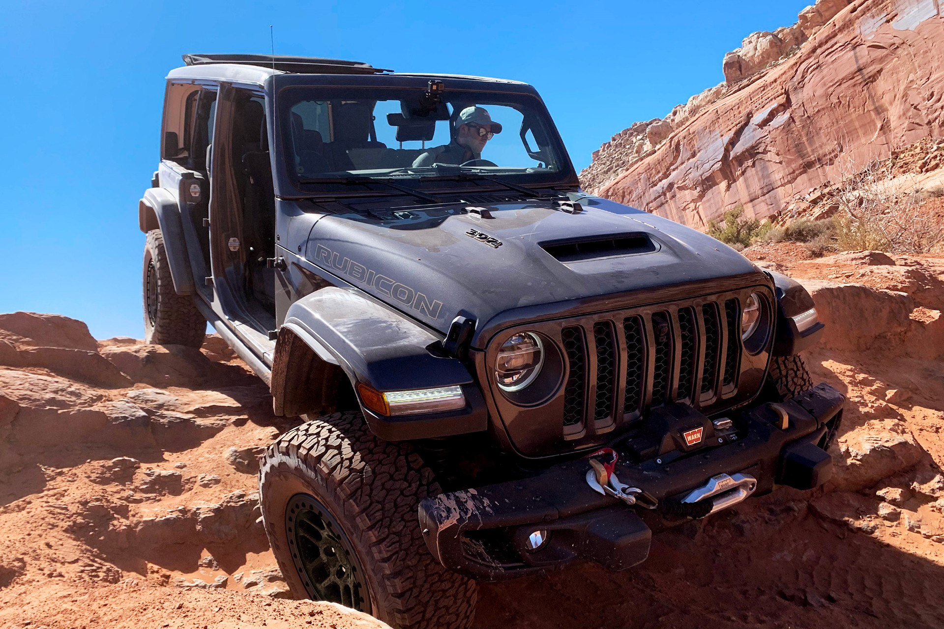 Blue 2022 Jeep Wrangler parked downhill on a rocky terrain.