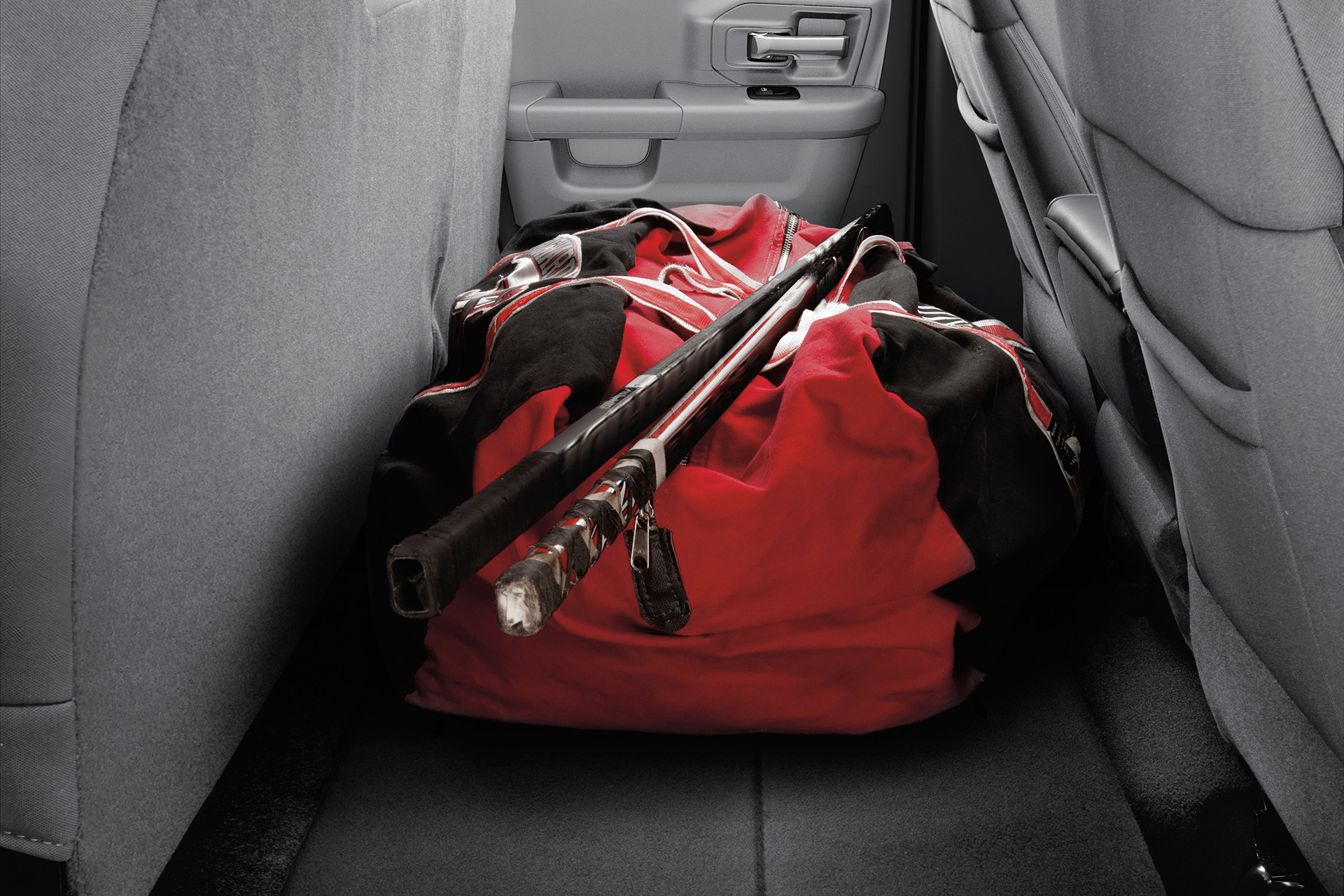 The rear seats of a 2022 Ram 1500 Classic, folded to create space for hockey sticks and a hockey bag.