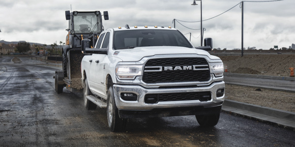 White 2021 Ram 2500 towing an excavator