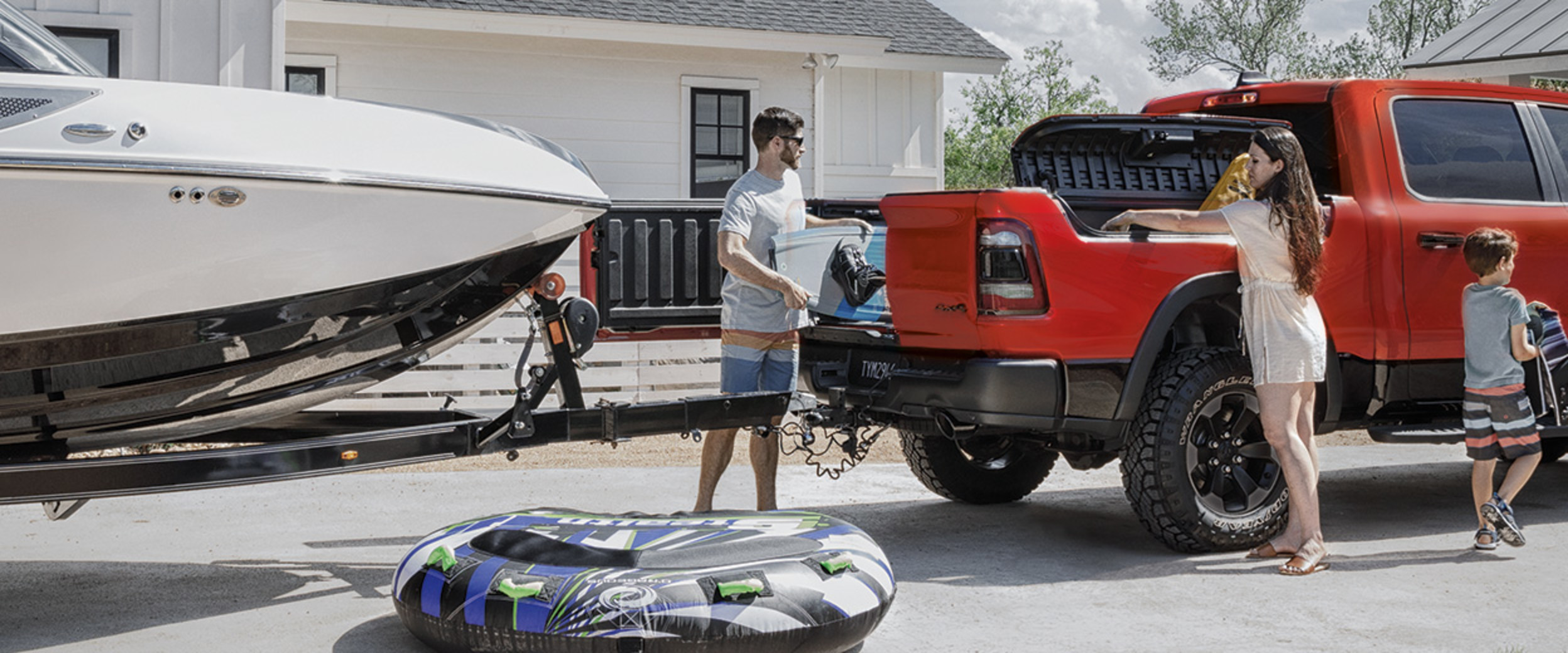 A family unloading a Ram 1500 with one door of its multifunction tailgate open.