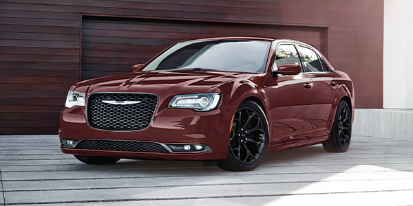 Velvet Red 2022 Chrysler 300 parked in front of a garage.