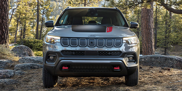 The front of a grey 2022 Jeep Compass parked in a forest.